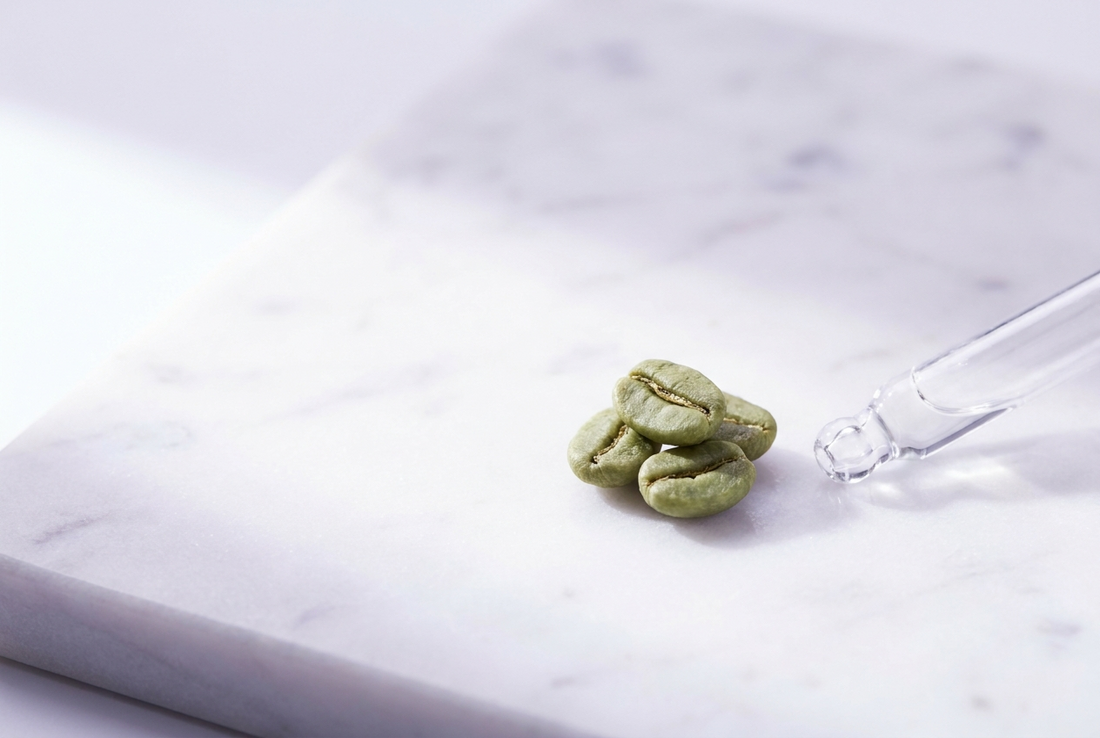 Caféine en cosmétique pour le contour des yeux : grains de café verts et pipette sur marbre blanc